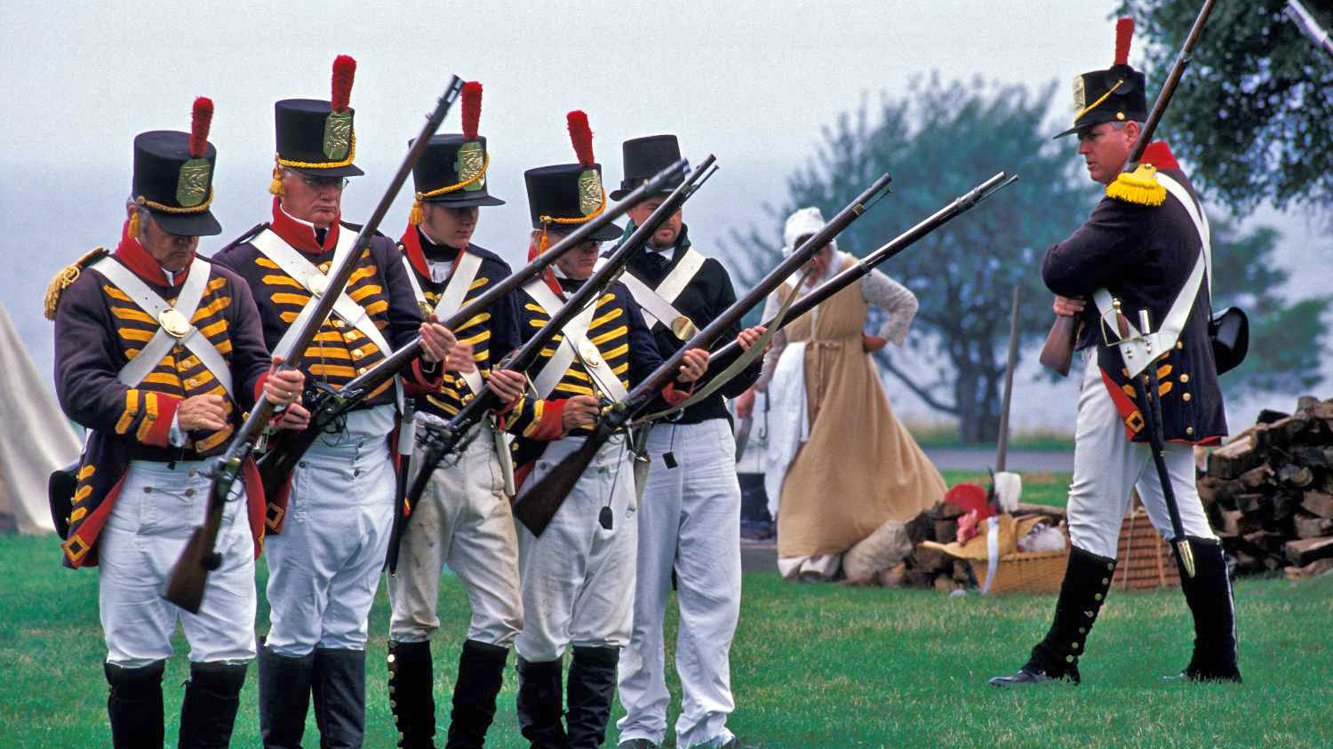 Photo of reenactors in uniform loading rifles on the Sackets Harbor Battlefield