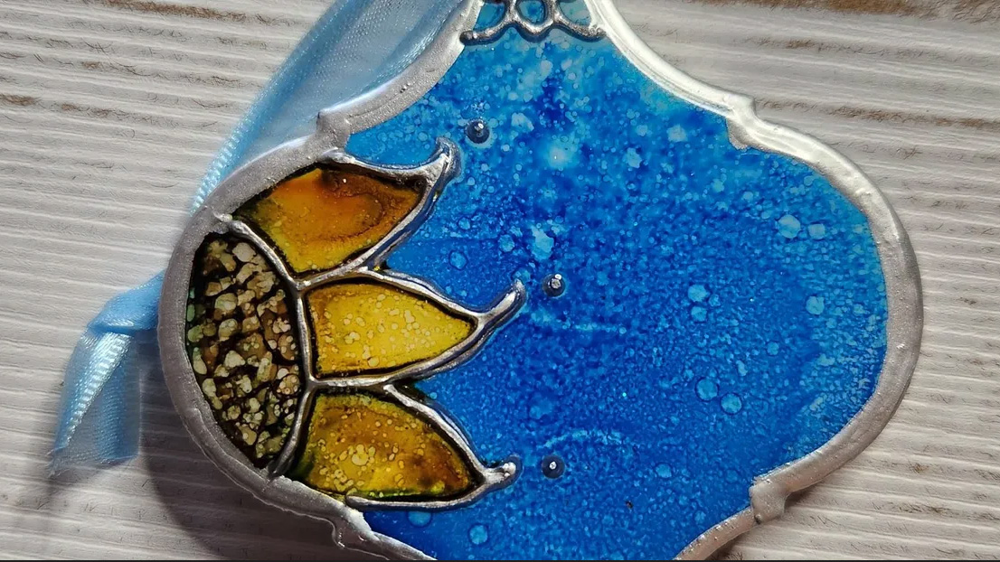 A blue and gold ornament, edged with silver, from the Tiny Art Show at the Sackets Harbor Arts Center