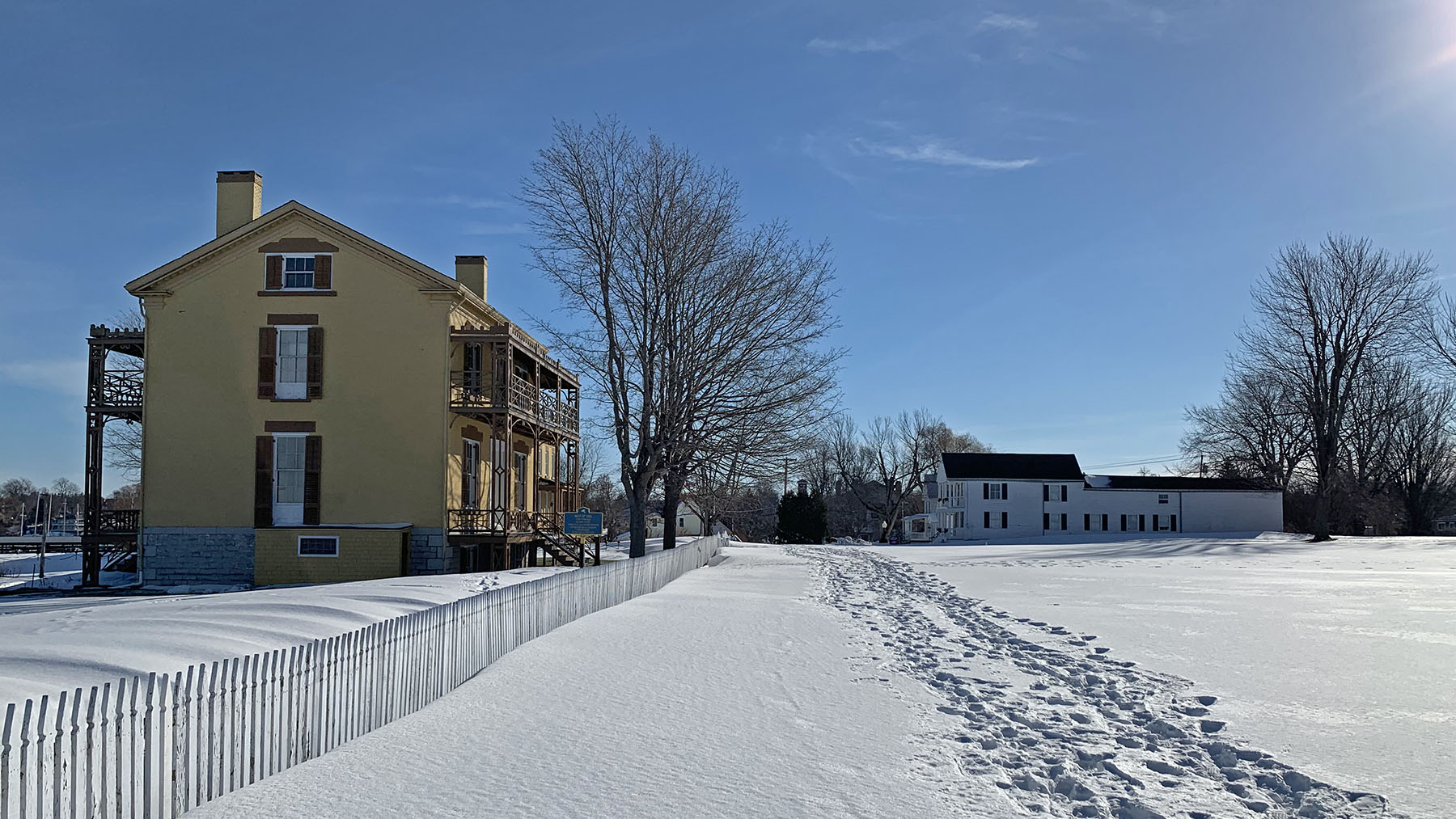 Color photo of the Sackets Harbor Battlefield's History Trail covered in snow on a sunny day