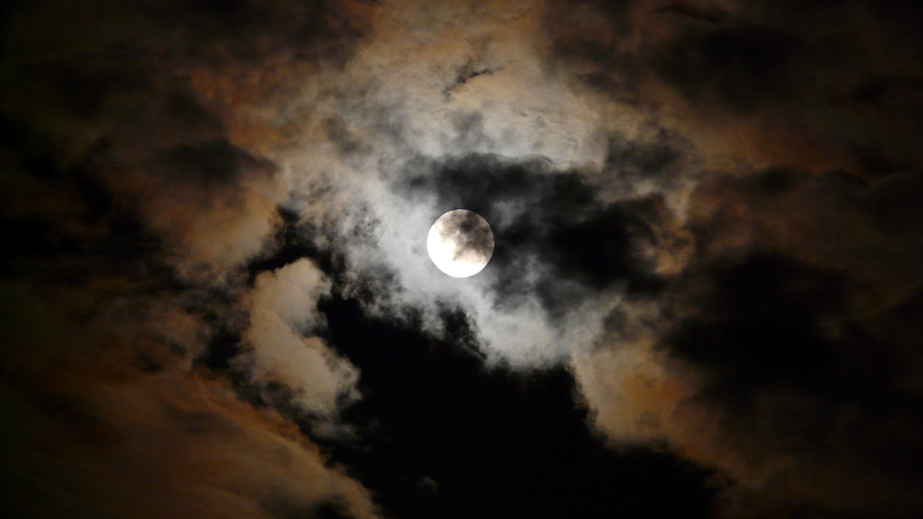 Stock photo of clouds moving across the night sky in front of a full moon (Creative Commons photo)