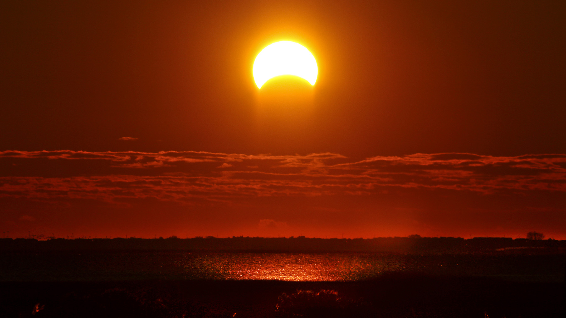 Stock photo of a partial eclipse over water (Creative Commons image, courtesy of RawPixel.com)