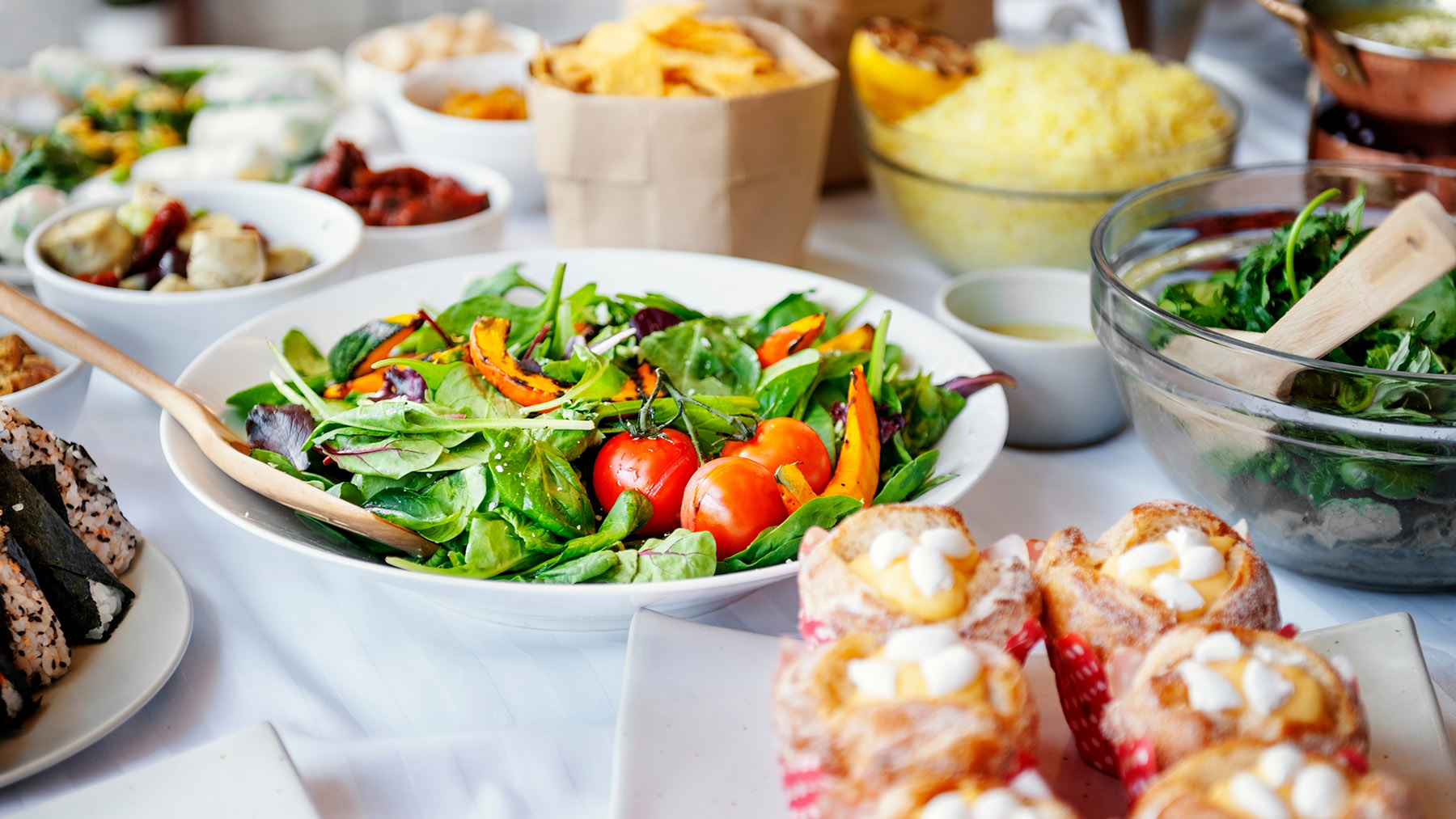 Stock photo of a table filled with fresh salads and other dishes (Image courtesy of RawPixel.com)